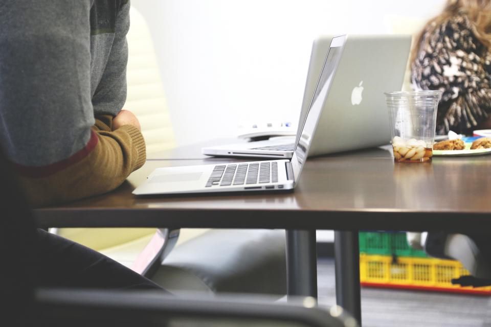 Zwei Personen sitzen an einem Tisch mit aufgeklappten Laptops, Symbolbild