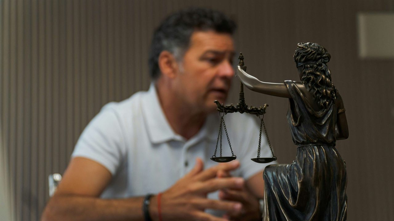 Justitia-Figur im Vordergrund, dahinter ein Mann im Gespräch