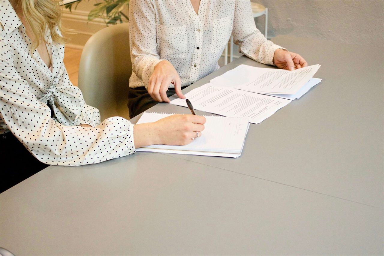Zwei Personen prüfen ausgedruckte Verträge und machen sich Notizen
