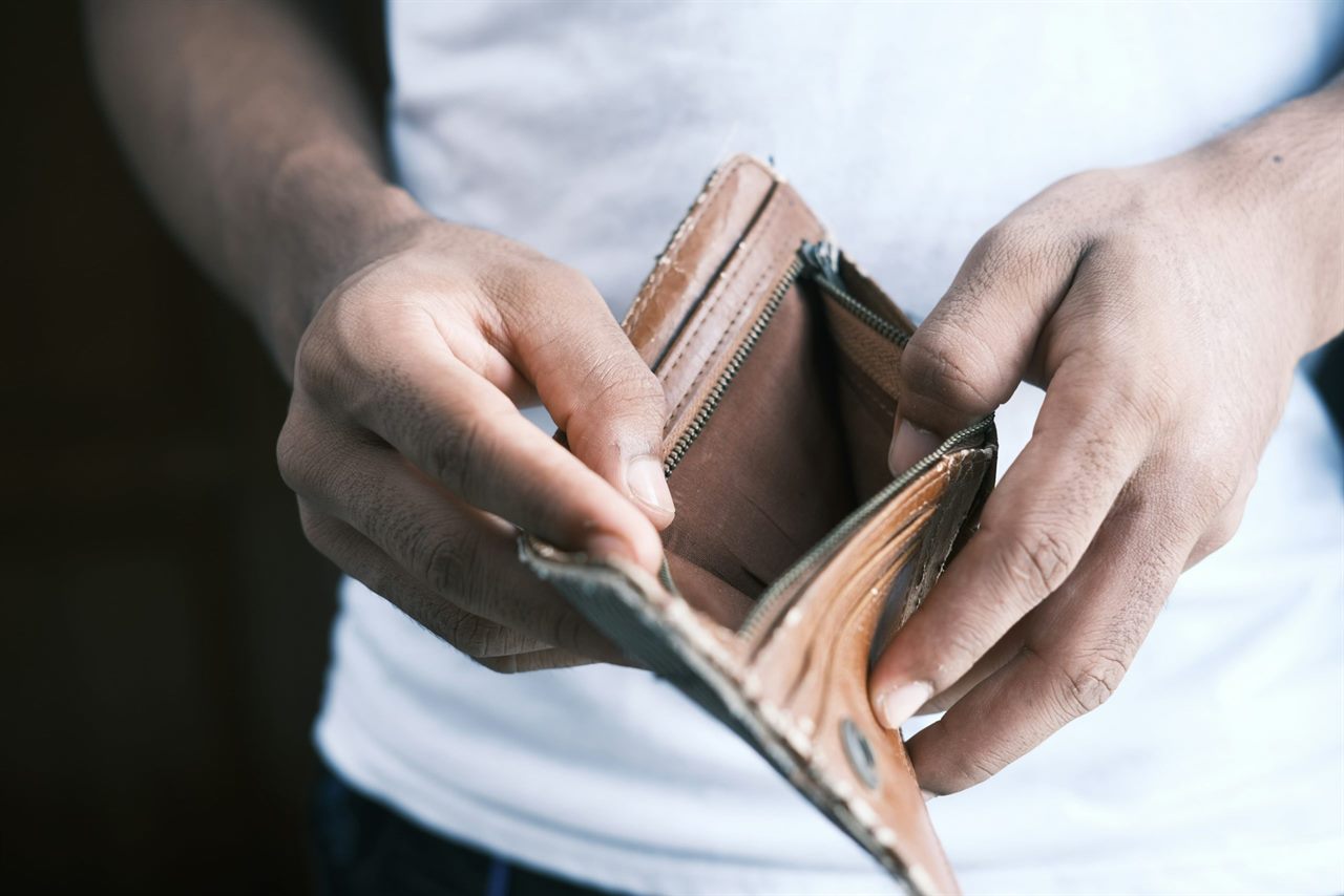Hände halten eine geöffnete, leere Geldbörse, Symbolbild für Insolvenzrecht